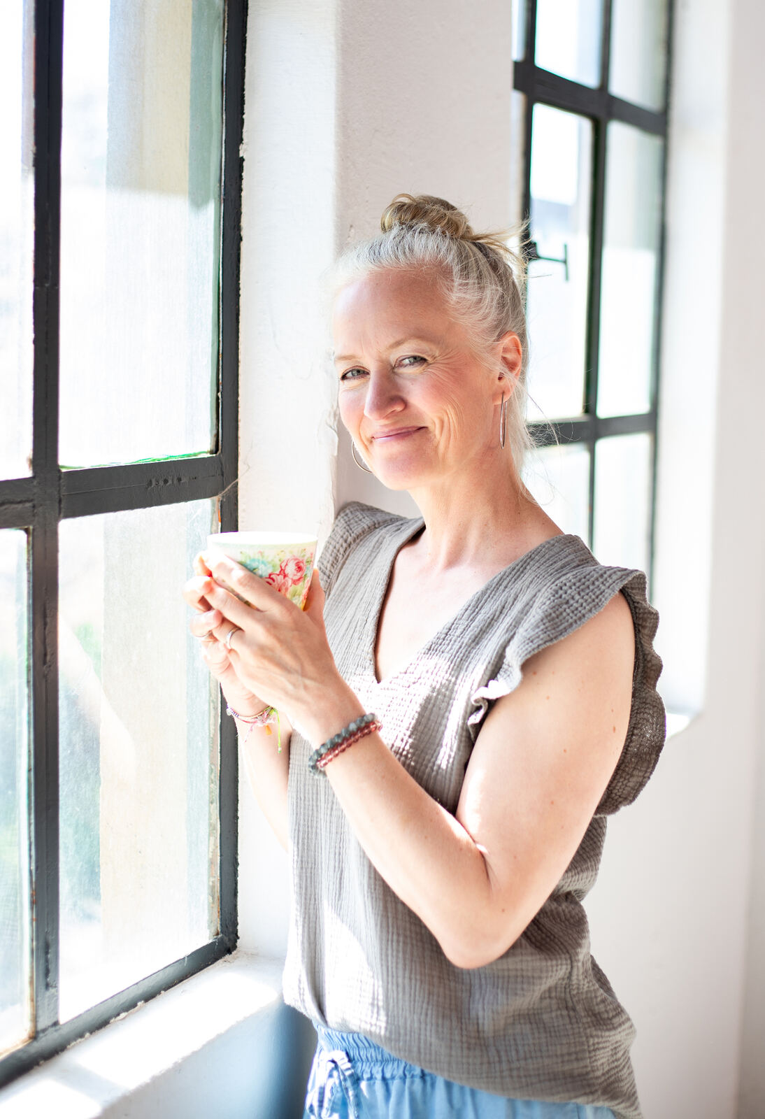 Sonja Klein mit einer Tasse am Fenster